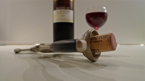 Opener w/ cork staged in front of bottle and wine glass